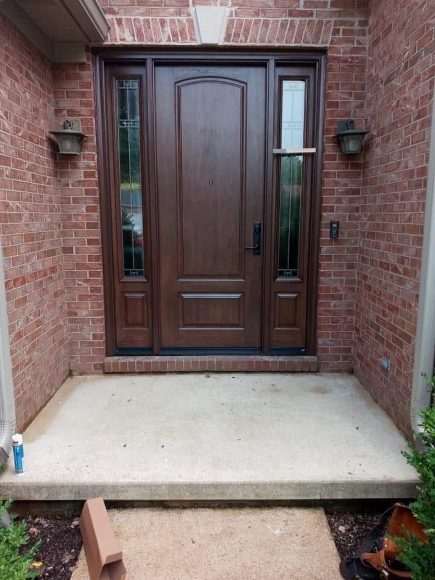 Finished dark wood front entry door with sidelights on a brick home