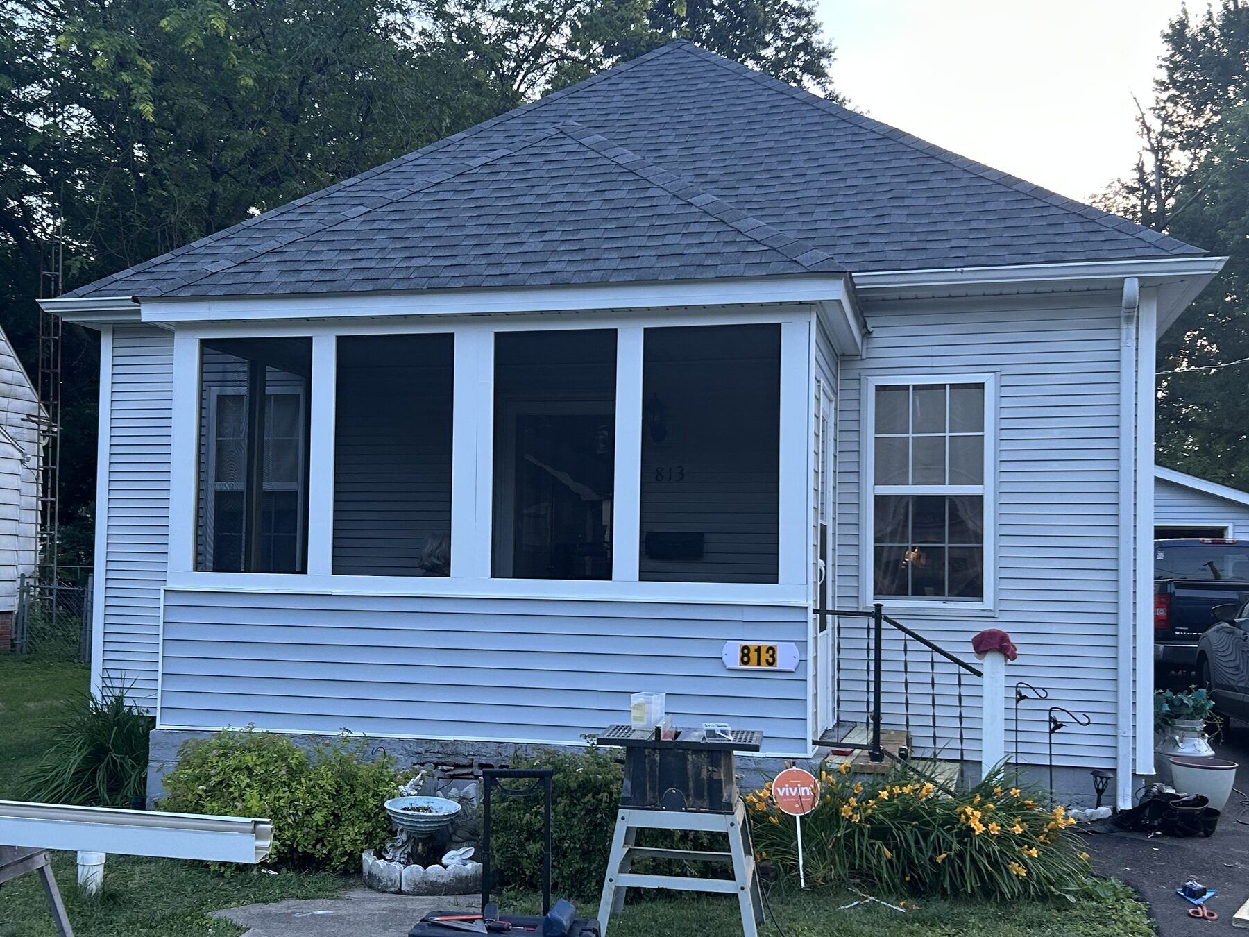 Finished bungalow with a closed-in screened porch, new light grey siding, white trim and a new roof